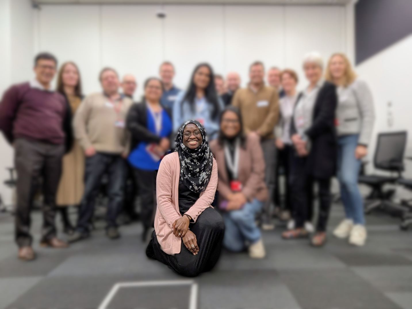 Olayinka kneeling and smiling in front of a group of leaders after a workshop